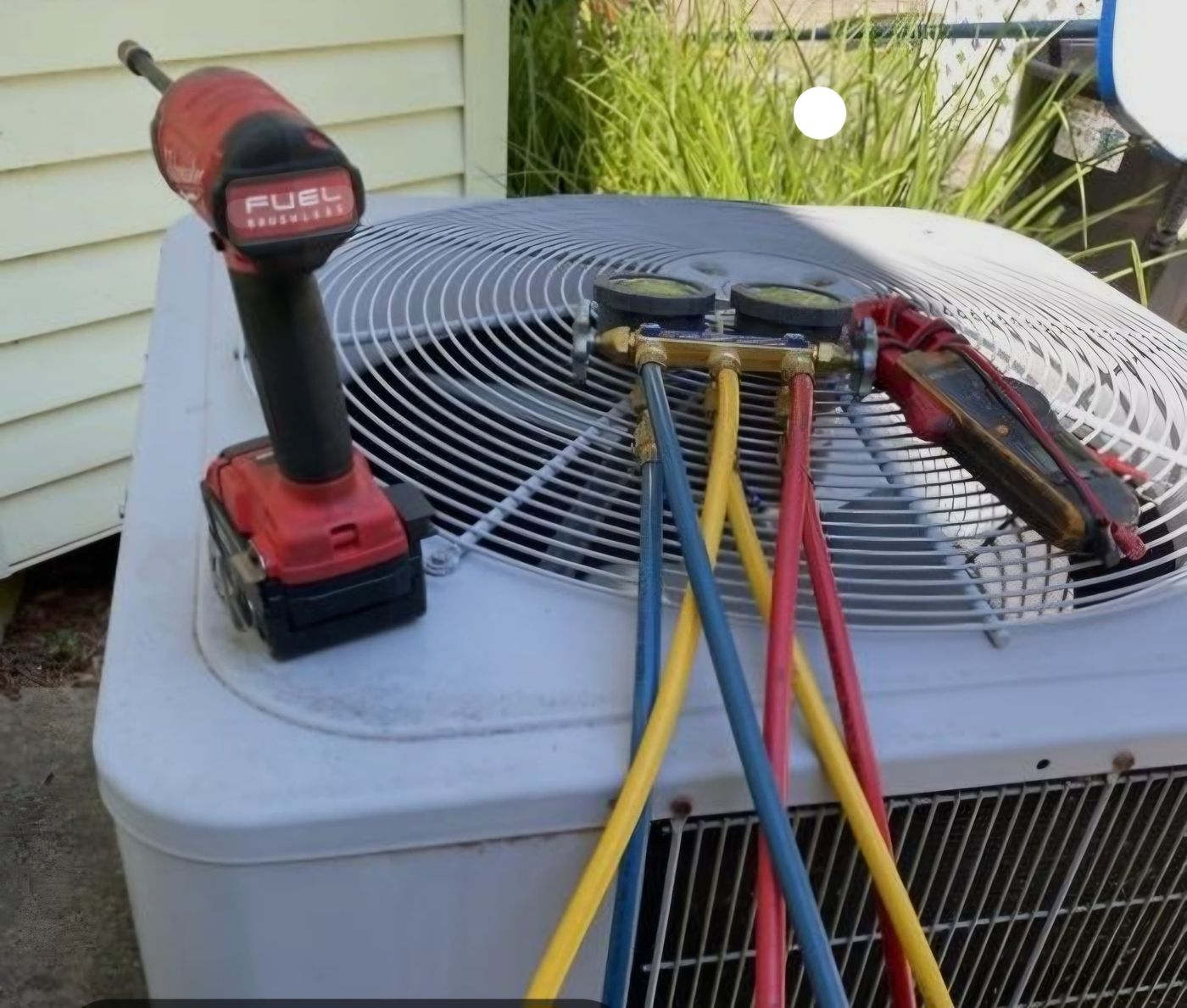 Refrigerant manifold gauges connected to an outdoor AC condenser during service